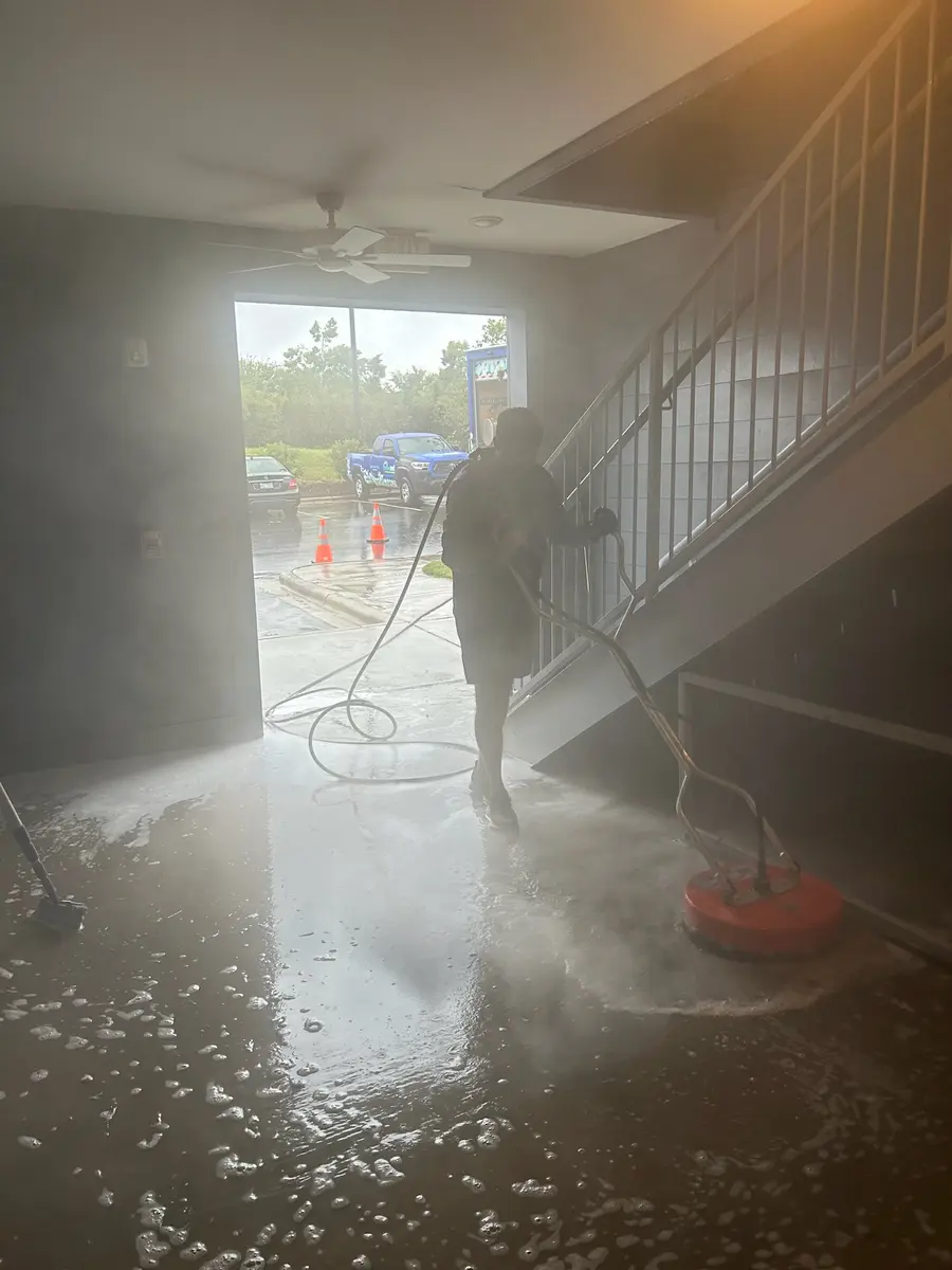 Worker cleaning an apartment building corridor and stairwell entrance, action shot.